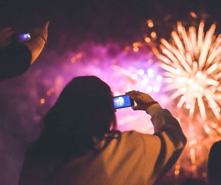 Woman taking a picture of a fireworks display.