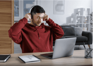 man putting on headphones in front of laptop computer